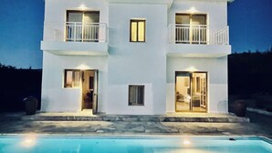 Casa blanca de dos pisos con piscina delantera.
