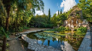 Un jardín tranquilo con un estanque, senderos de piedra y estatuas.