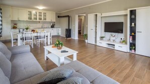 Una sala de estar moderna con un sofá gris, una mesa de centro con una planta y un mueble de televisión con televisor de pantalla plana.