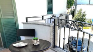 A balcony with a round table, two chairs, and a potted plant. - Bright Apartment a few km From the sea (Minervino di Lecce)