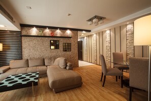 A modern living room with a sectional sofa, a glass-top coffee table, and a seating area with chairs.