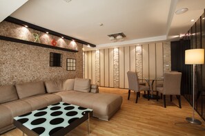 A modern living room with a sectional sofa, a coffee table with a polka dot pattern, a dining area with a small table and chairs, and a tall floor lamp.