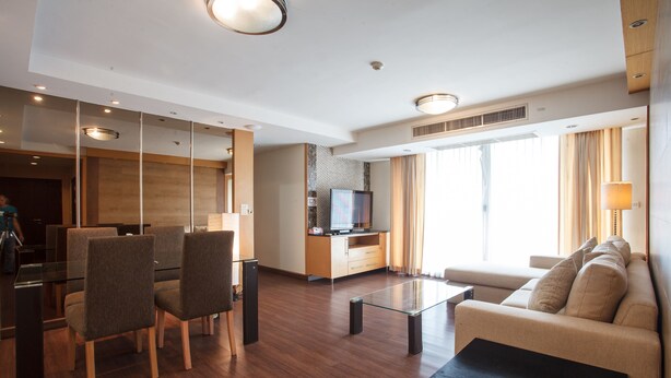 A modern hotel room with a dining area, a sofa, and a TV. - 3A - 2 Bedroom Downtown Apartment With Shared Pool (Bangkok)