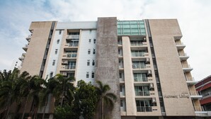 A multi-story Harmony Living building with a central concrete pillar, balconies, and a clear sky. - 3A - 2 Bedroom Downtown Apartment With Shared Pool (Bangkok)