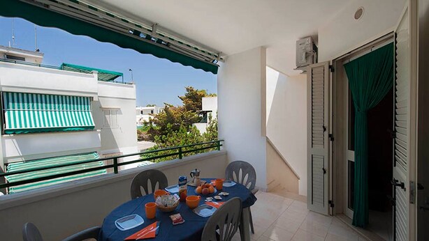 Ein Balkon mit Esstisch, Stühlen und Blick auf benachbarte Gebäude.