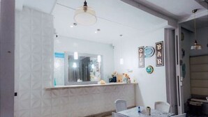 Uma sala de jantar com mesa e cadeiras, piso estampado e espelho sobre o balcão.