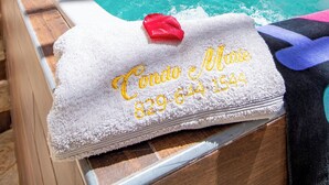 Un espace piscine doté d’une terrasse en bois, d’un mur en briques et d’une serviette sur laquelle est inscrit un numéro de téléphone.