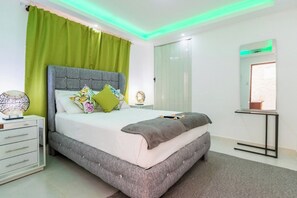 A bedroom with a bed, a bedside table, a mirror, and a green curtain. - Room-cozy 1bd With Common Jacuzzi (Sosúa)