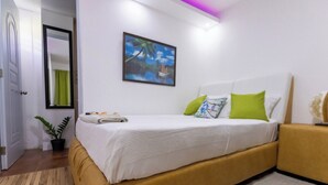Un dormitorio con cama, un cuadro, una planta en maceta y una puerta.