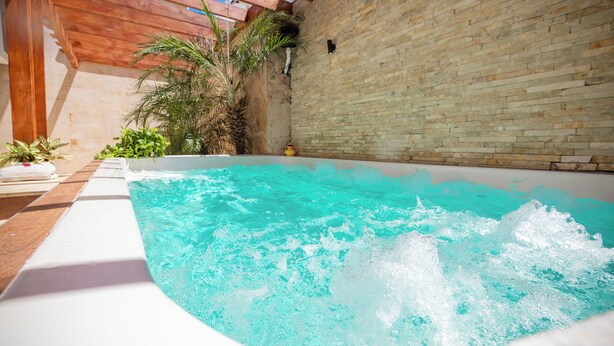 Un jacuzzi con una pérgola de madera y un muro de ladrillo.