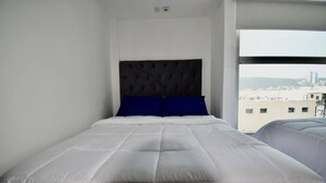 Een hotelkamer met een groot bed, een hoofdbord en een raam met uitzicht op de stad.