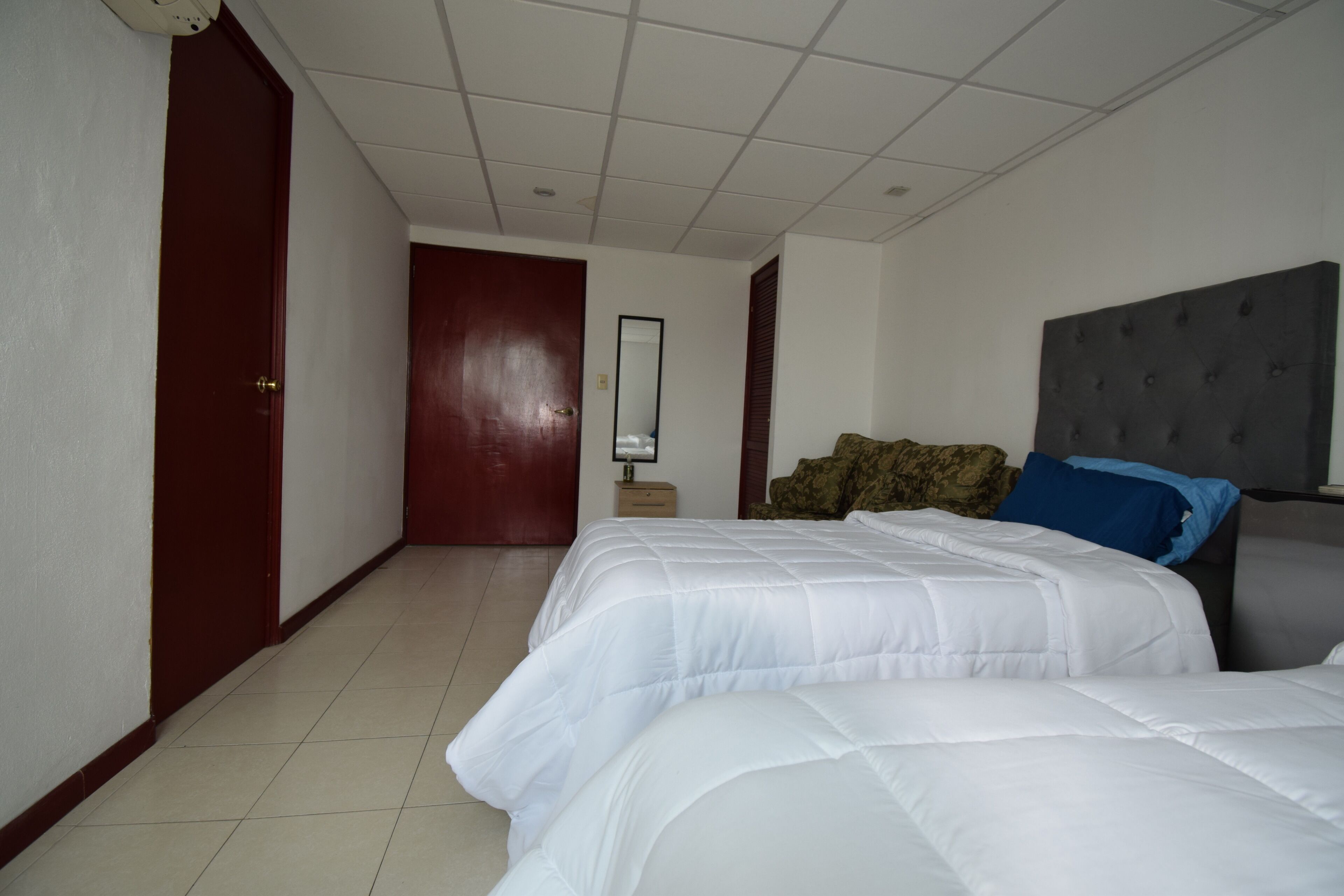 A hotel room with two beds, a large mirror, and a wardrobe.