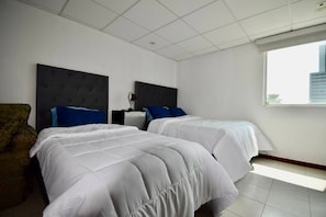 A hotel room with two beds, a chair, and a window with a view of buildings. - Habitacion Tipo Hotel En Obispado (Monterrey)