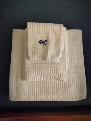 A neatly folded white towel with a blue bow on a dark surface.