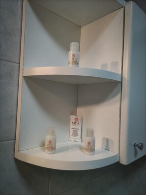 Un bagno con un vanità bianca e mensole con articoli da toilette.