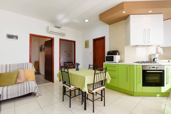 A compact living space with a dining area, kitchenette, and a sofa.