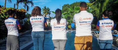 A group of staff members standing by a pool with palm trees in the background.