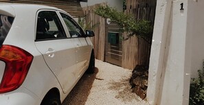 A white car parked in a driveway with a wooden fence and a gate. - Ti Baz Beach House With Mountain View (Tamarin)