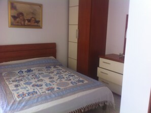 Une chambre à coucher avec un lit, une commode, un miroir et un tableau accroché au mur.