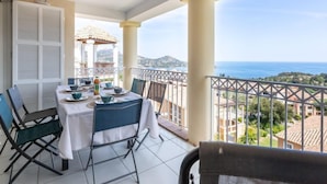 Un balcón con una mesa lista para comer, con vista al mar.