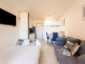 A hotel room with a bed, a sofa, a desk, and a kitchenette.