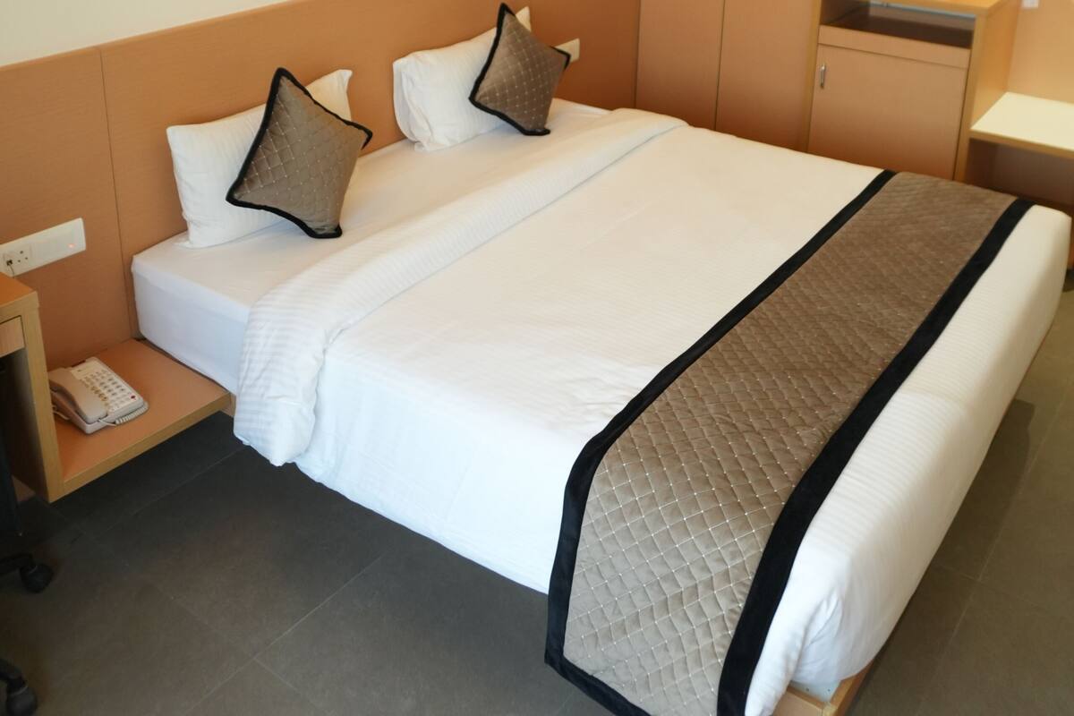 Ein Hotelzimmer mit Bett, Nachttisch, Kleiderschrank und einem Bild an der Wand.