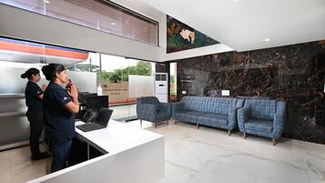 A modern reception area with a white desk, two sofas, and a large mural on the wall.