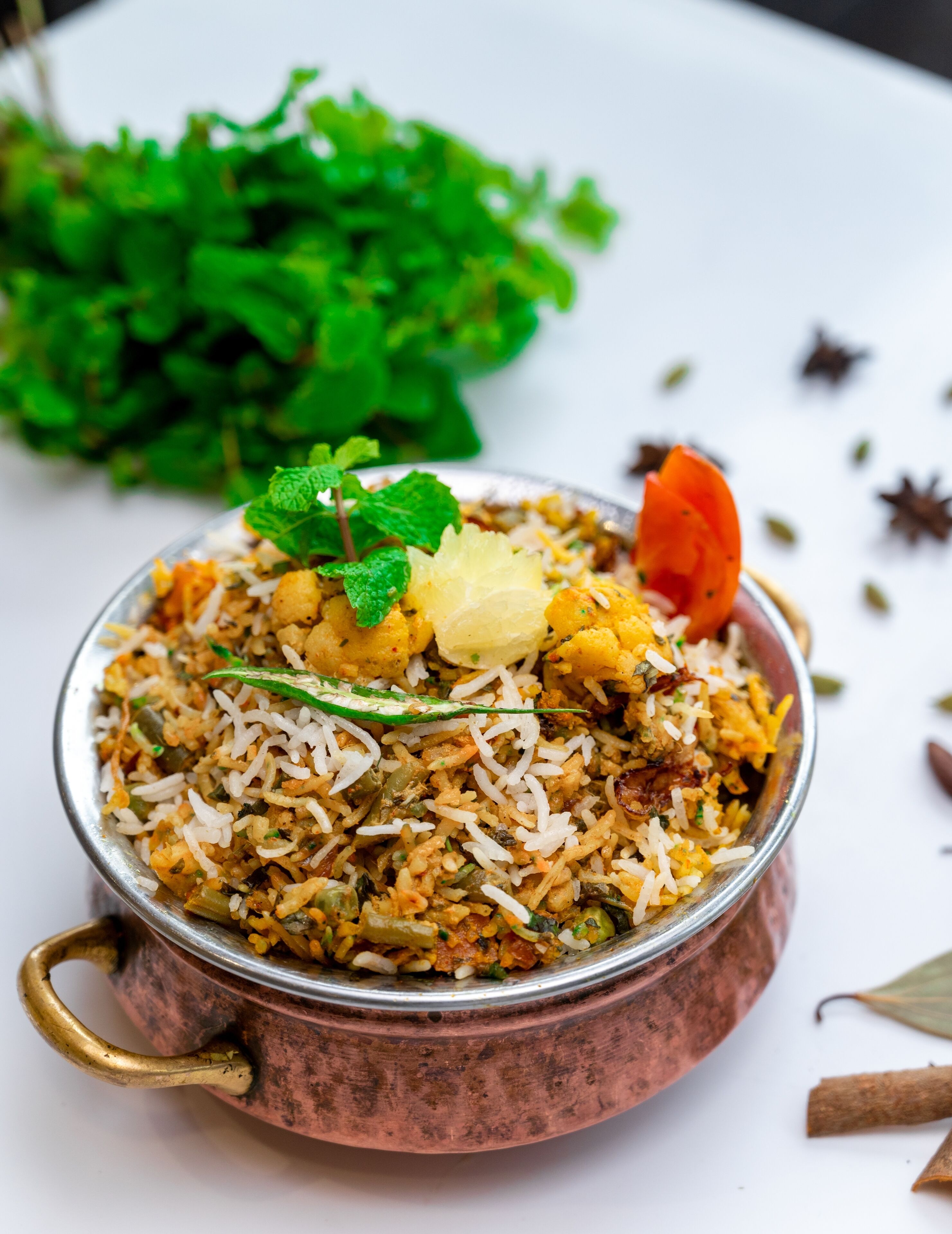 A bowl of biryani with vegetables and garnishes.
