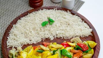 A wooden plate with white rice and a colorful vegetable stir-fry.