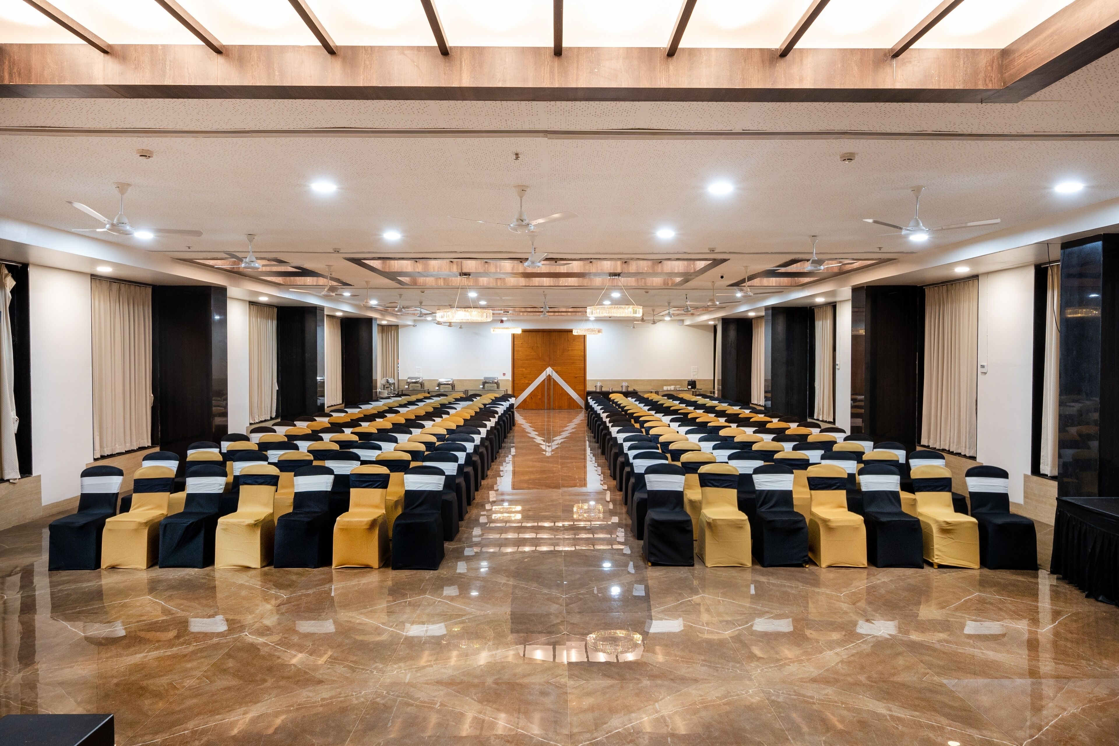 A conference room with rows of chairs, ceiling fans, and recessed lighting.