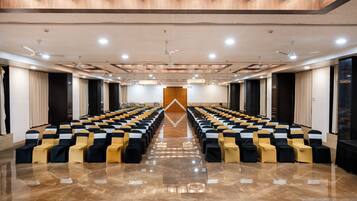 A conference room with rows of chairs, ceiling fans, and recessed lighting.