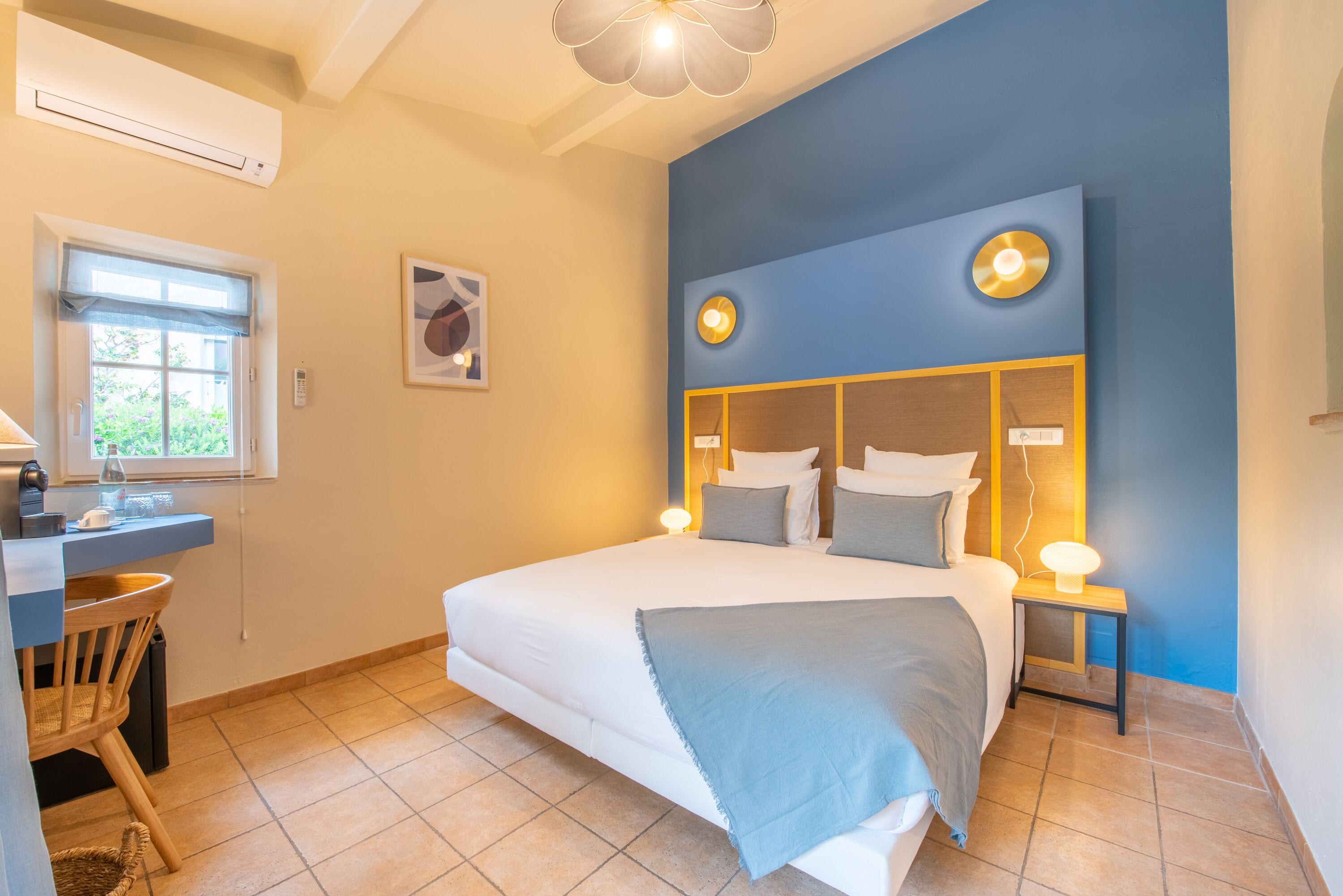 Un dormitorio con cama, mesitas de noche, escritorio y silla.