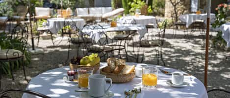 An outdoor dining area with round tables, white tablecloths, and metal chairs.