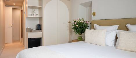 Un dormitorio con cama, mesita de noche, armario y una puerta que da a otra habitación.