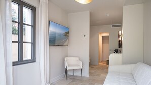 Un salon moderne avec un canapé blanc, un fauteuil et une grande fenêtre agrémentée de rideaux.
