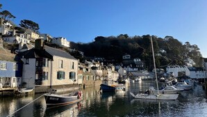 A harbor with boats docked, a building with a white facade, and a hillside with houses. - Stunning Views of Polperro Harbour from this Waterfront Cottage. Free Parking. (Polperro)