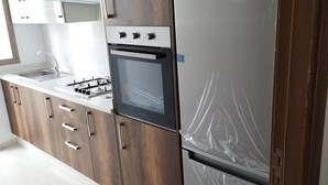 A modern kitchen with wooden cabinets, a stainless steel refrigerator, and a built-in oven. - Apartment (Bouznika)