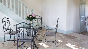A dining area with a glass table and metal chairs, a chandelier, and a staircase. - Orangerie. (Saint-Justin)