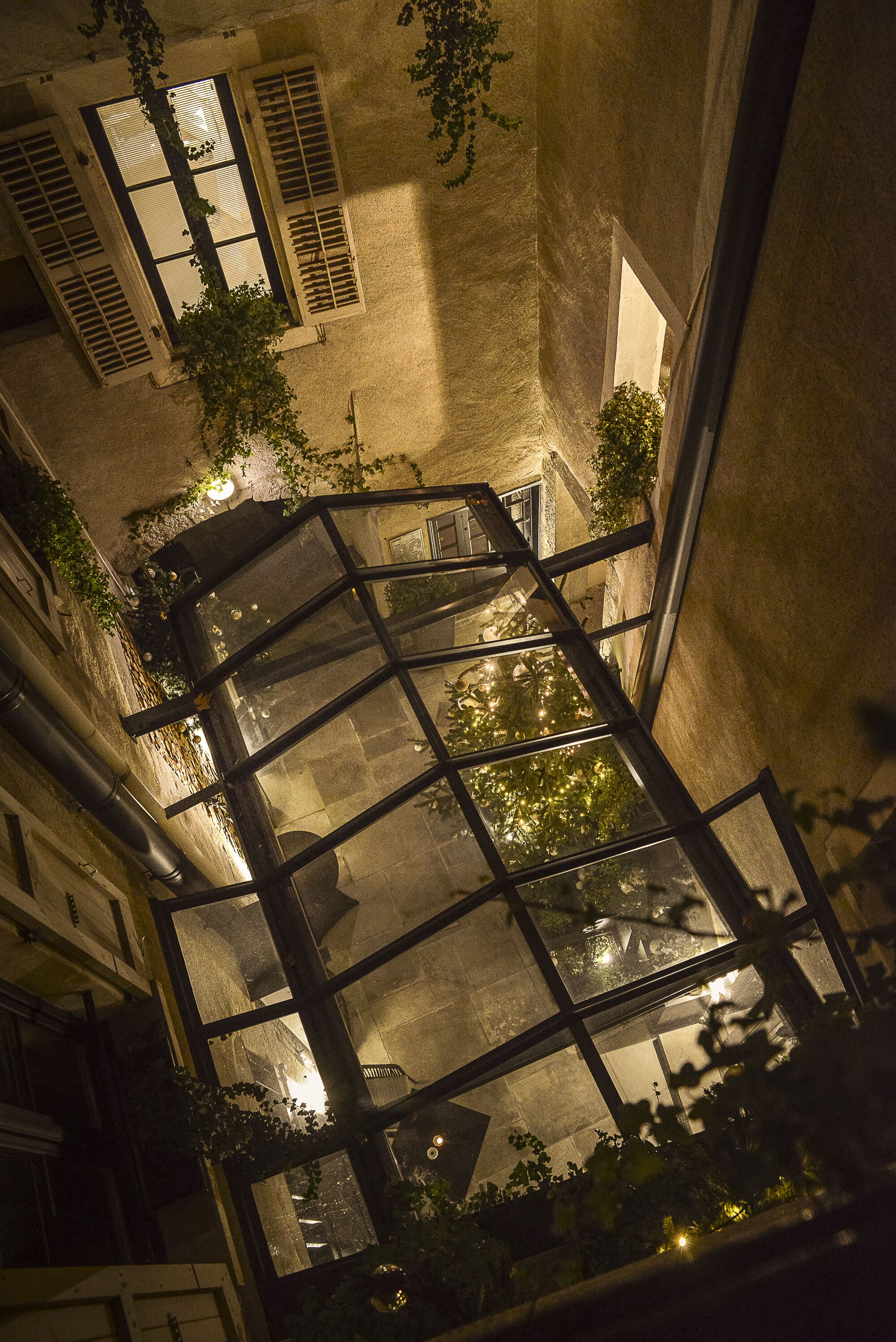Vista nocturna del interior de un edificio con varias ventanas y una escalera.