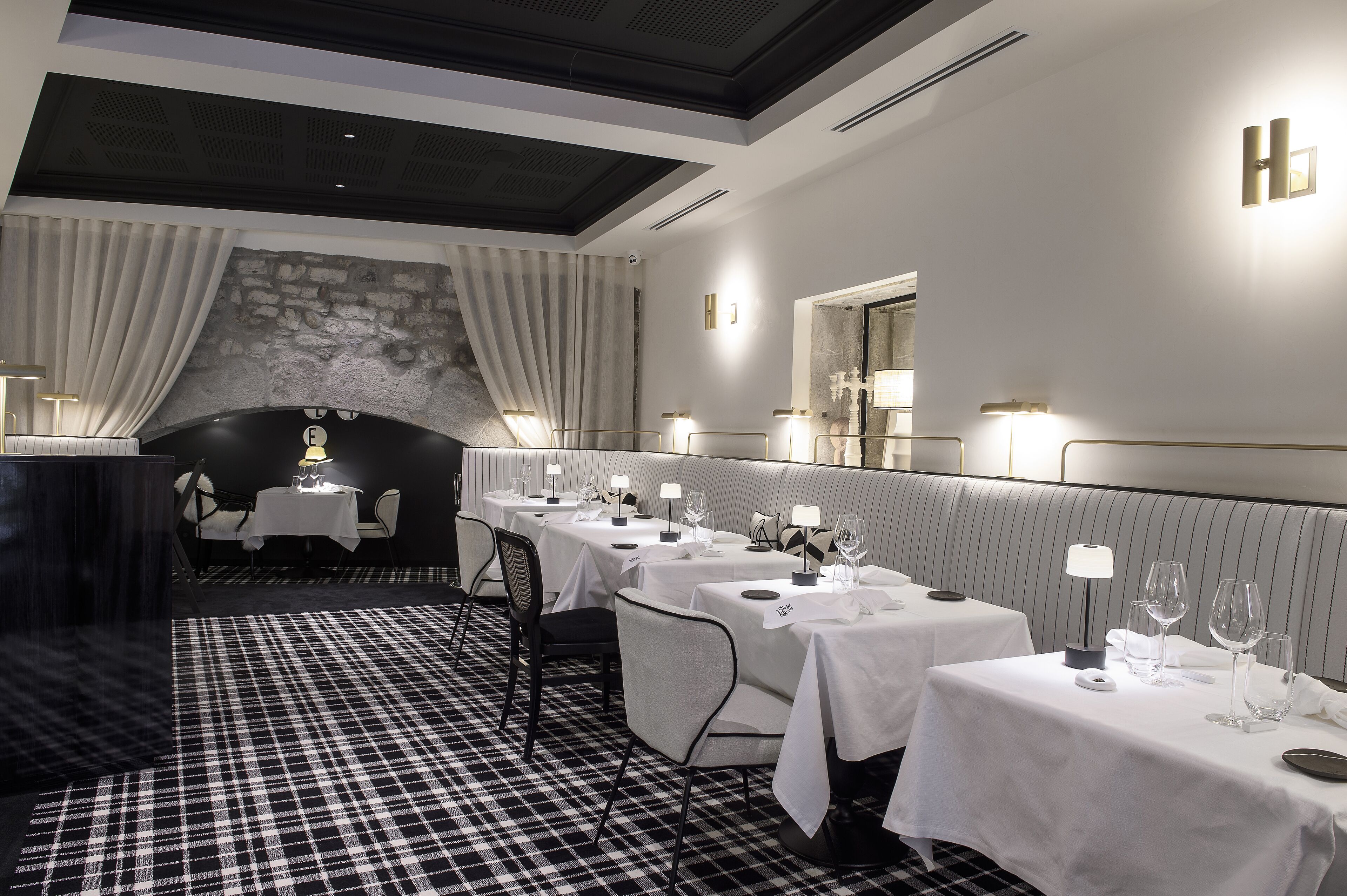 A restaurant with a checkered floor, white tablecloths, and candlelit tables.