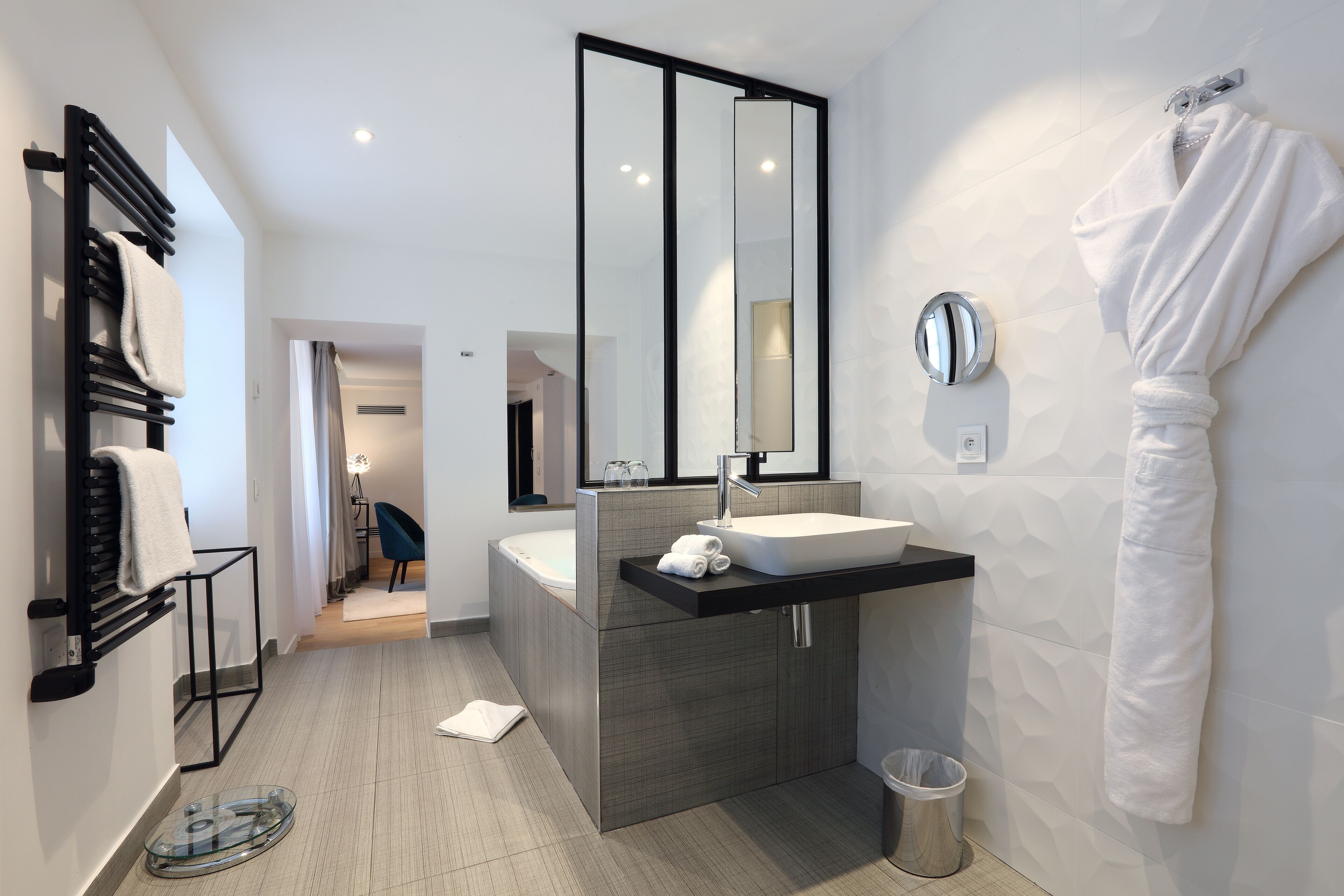 Une salle de bain moderne avec un grand miroir, un lavabo et un porte-serviettes.