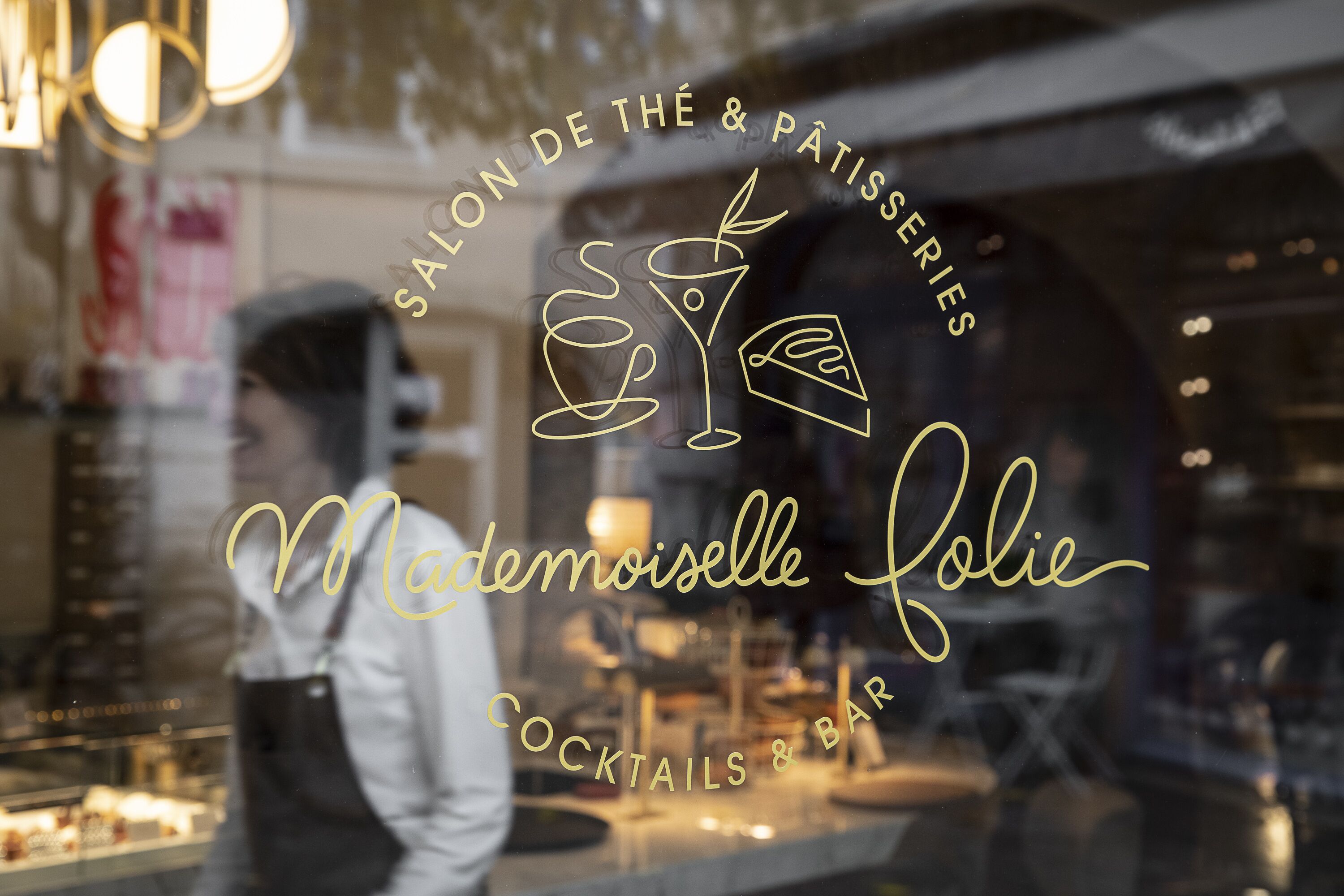 A storefront with a sign reading "Salon de Thé & Pâtisserie" and "Madémoiselle Jolie Cocktails & Bar".