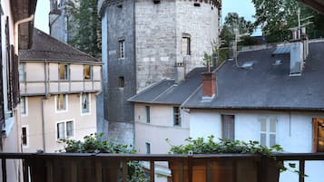 Ein Blick auf einen Turm mit einem Zinnenturm, umgeben von Gebäuden mit Balkonen und einer Straße darunter.