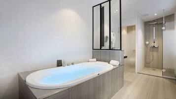 Un baño moderno con una bañera grande, cabina de ducha de vidrio y un espejo sobre el lavamanos.