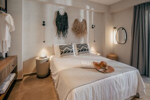 Une chambre à coucher avec un lit, des tables de chevet, un luminaire suspendu et un miroir au mur.