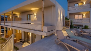 A modern hotel with a spacious outdoor area featuring sun loungers and a covered terrace.