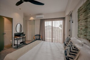 Une chambre d’hôtel avec un lit, une coiffeuse avec un miroir, une chaise et une fenêtre avec des rideaux.