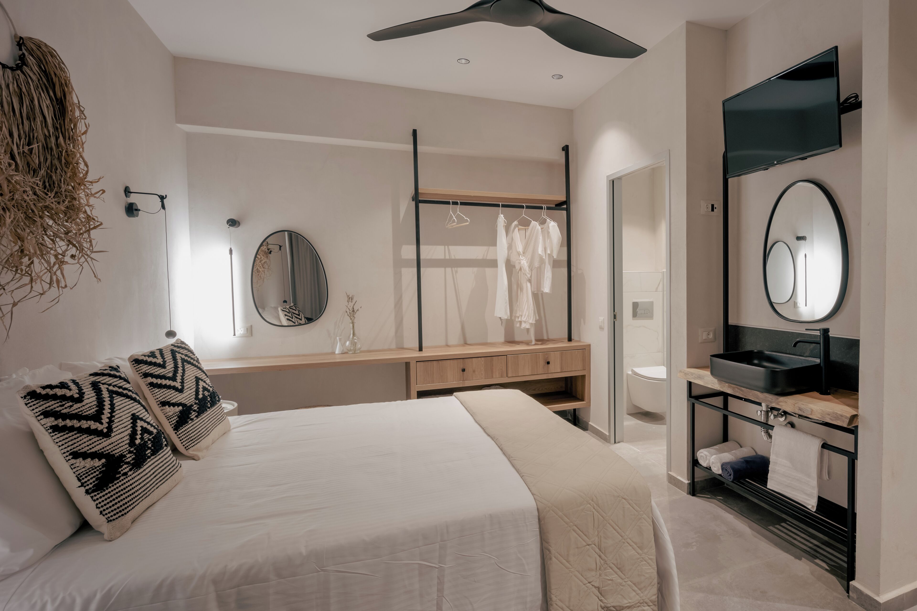 Une chambre à coucher moderne comprenant un lit, des tables de chevet, un miroir, une armoire et une salle de bain avec un lavabo et un miroir.