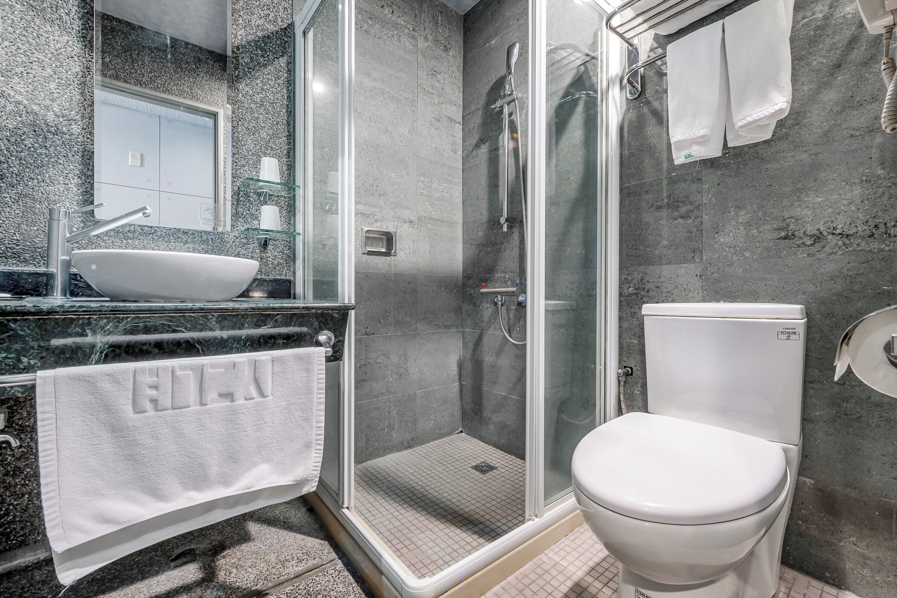 Un baño moderno con ducha de vidrio, un lavabo blanco y un inodoro.