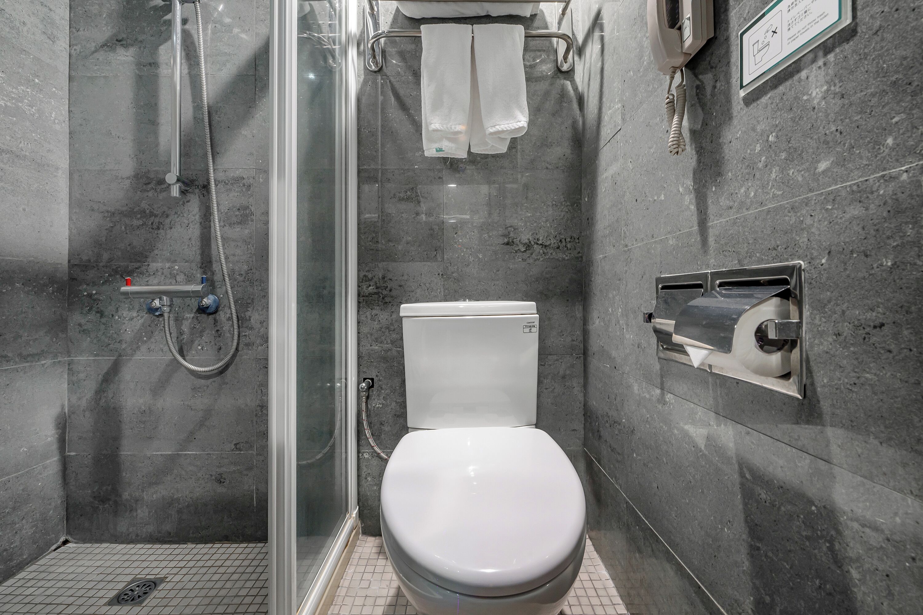 Une salle de bain moderne dotée d’une douche à parois de verre, de toilettes et d’un distributeur d’essuie-tout.